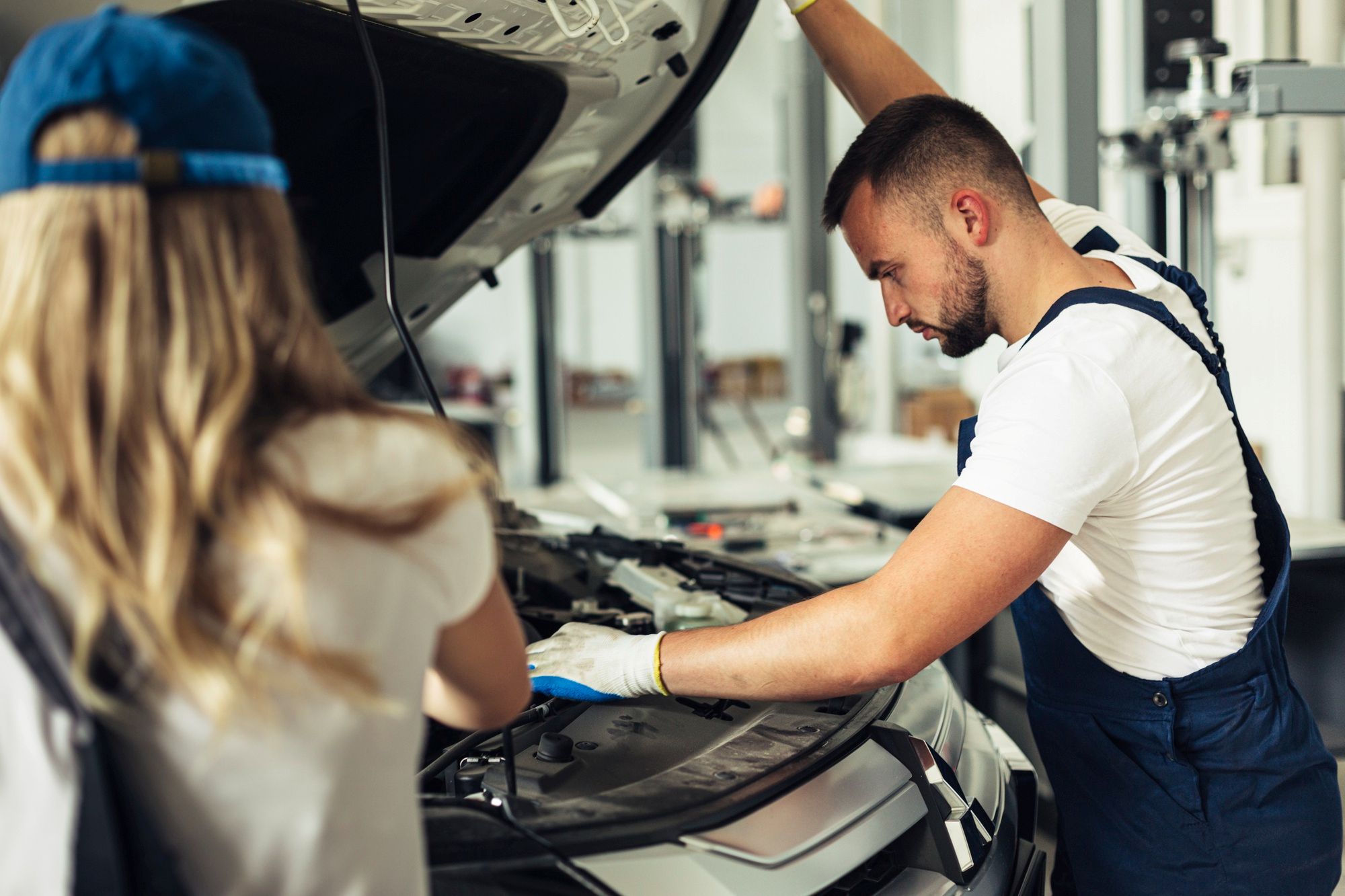 Recht auf Reparatur 2026, eine Kundin steht vor Ihrem Auto, ein Mechaniker checkt den Schaden