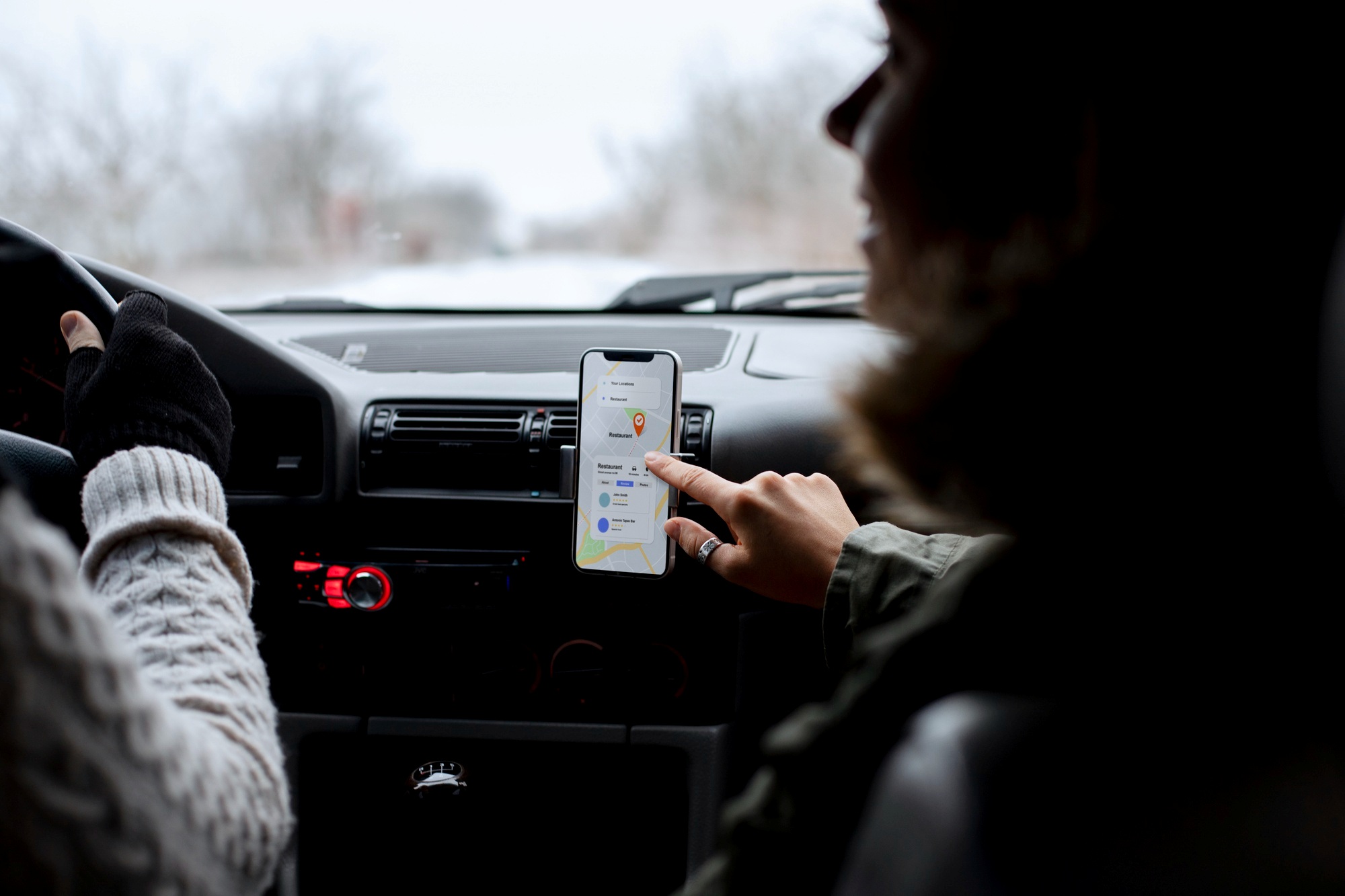 Blitzer-App und Dashcam, eine junge Frau zeigt auf ein Smartphone mit Blitzerwarner